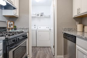A kitchen with a black stove top oven and a white dishwasher.