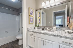 A bathroom with a toilet, sink, and mirror.