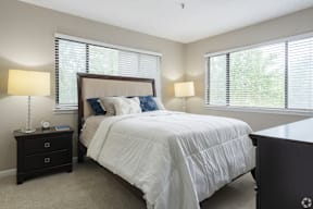 A bedroom with a large bed, two lamps, and a nightstand.