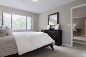 A bedroom with a bed, dresser, and mirror.