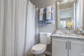A white toilet in a bathroom with a white shower curtain.