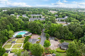 An aerial view of a residential area with a swimming pool and trees.