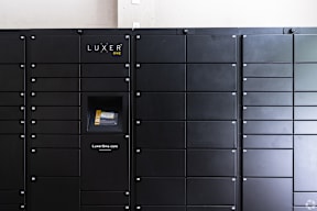 A black wall with a slot in the middle and the word LUXER above it.
