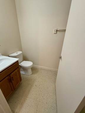 A white toilet sits in a small bathroom next to a sink.