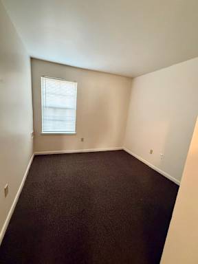 A room with a window and carpeted floor.