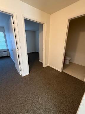A room with carpeted floor and two open doors.