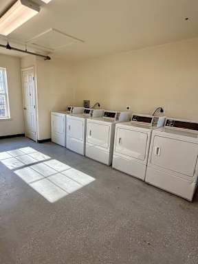 A row of washing machines are lined up in a laundry room.