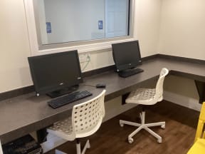 a desk with two computer monitors and two chairs