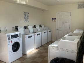 a laundry room filled with white washers and dryers