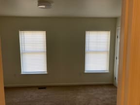 an empty room with two windows and a door