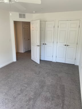 a bedroom with a carpeted floor and a closet with a door open