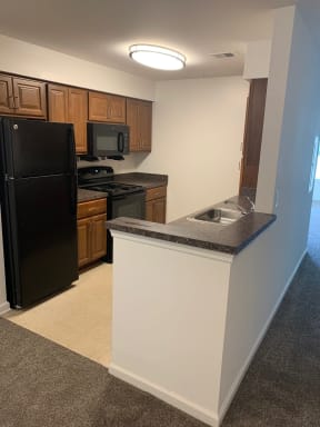 a kitchen with a black refrigerator freezer next to a stove top oven