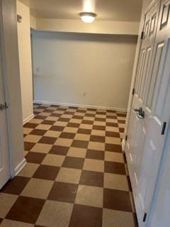a hallway with a checkered floor and a white door