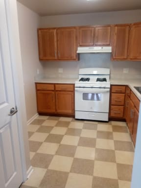 a kitchen with a white stove top oven and a checkered floor