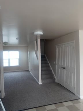 an empty room with a white door and stairs