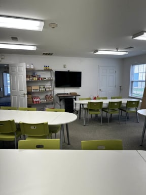 a classroom with green chairs and white tables