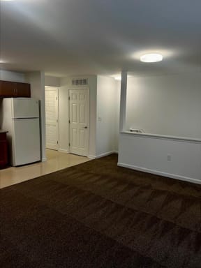 an empty room with a refrigerator and a door