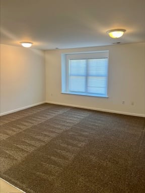 an empty room with a window and a carpeted floor