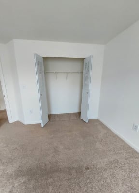 an empty bedroom with a closet and a carpeted floor
