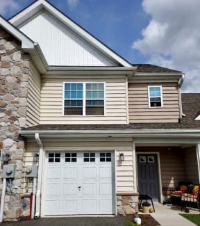 a house with a white garage door and a stone wall