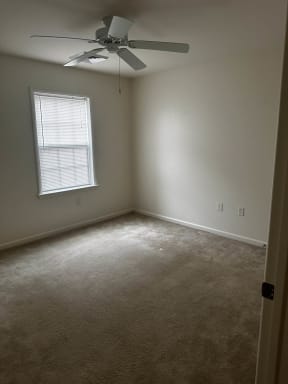 an empty room with a ceiling fan and a window