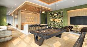 A pool table is in the middle of a room with a green wall and a sign that says "OFLORA".