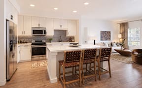 A modern kitchen with a large island and wooden chairs.
