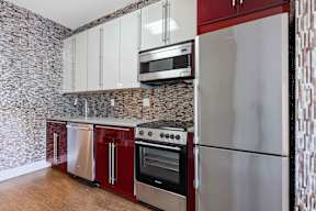 A kitchen with a refrigerator, oven, and microwave.