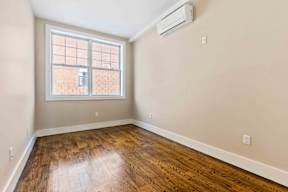 A room with a window and wooden flooring.