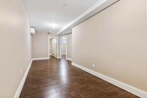 A long hallway with wood floors and white walls.