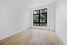 a room with white walls and a large window and wooden floors