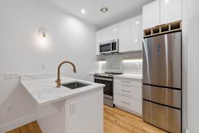 a kitchen with white cabinets and a stainless steel refrigerator
