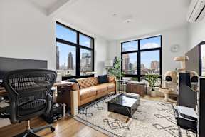 an open living room with a couch and a desk with a large window