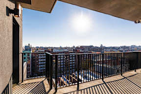 A balcony with a black railing and a view of a cityscape.
