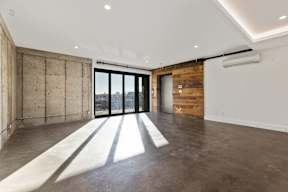 A room with a concrete wall and a sliding glass door.