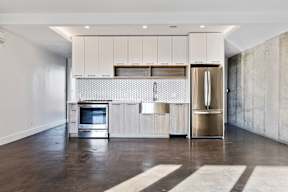 A modern kitchen with a refrigerator, oven, and cabinets.