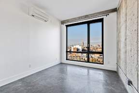 A large empty room with a view of a cityscape through a large window.