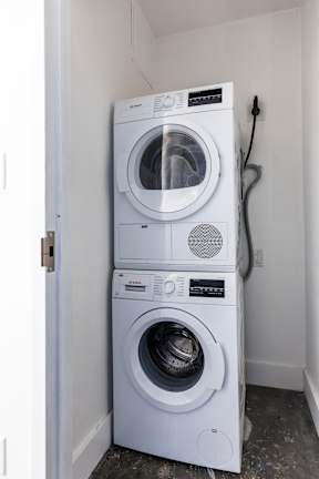 Two white front loading washing machines in a laundry room.
