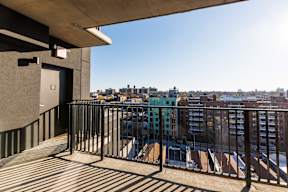 A balcony with a metal railing and a view of a city skyline.