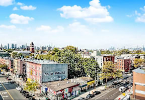 A city street with a view of the city skyline in the distance.