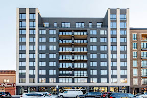 A large modern building with a lot of windows and cars parked in front.