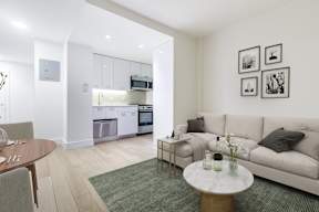 A modern living room with a kitchen in the background.