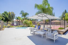 a patio with two lounge chairs and an umbrella with a pool in the background at Metro 3610, California