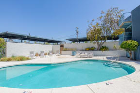 a swimming pool with lounge chairs and a tree in front of a building