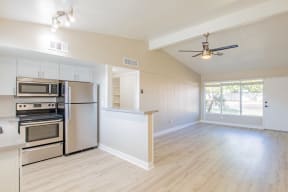 an empty kitchen and living room with a ceiling fan
