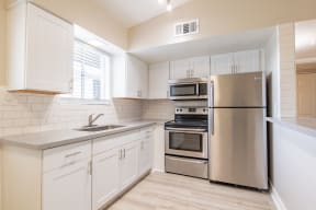 a kitchen with white cabinets and stainless steel appliances