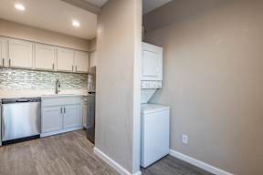 a kitchen with white cabinets and a white washer and dryer  at Sofia Apartments, Tempe