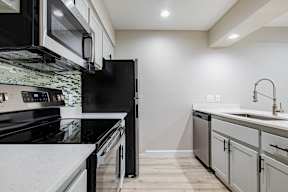 A modern kitchen with black appliances and white countertops at Sofia Apartments, Tempe, 85283