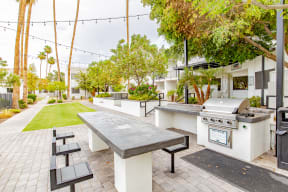 a patio with a barbecue grill and a table with benches