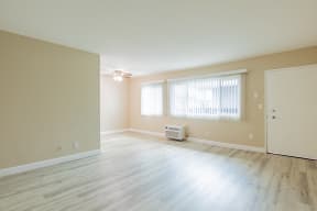 an empty living room with wood floors and a window